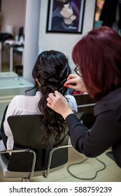 Close Up Of Hair Stylist Making A Braid On Long Brunette Hair In A Beauty Salon. Bridal Hairstyle. Wedding