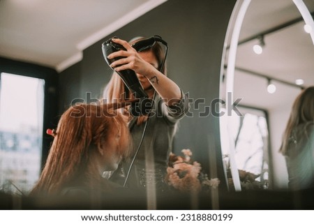 Close up of hairdresser blow drying her clients bangs while standing at the studio