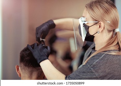 Close up hairdresser with security measures for Covid-19, cuts a man  social distance, cutting hair with a medical mask, face shield and rubber gloves. - Powered by Shutterstock