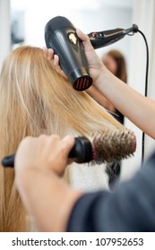 Close Up Of Hairdressers Hands Drying Long Blond Hair With Blow Dryer And Round Brush