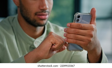 Close Up Half Face African American Bearded Man Indoors Male Customer Businessman Holding Smartphone Sitting At Home Office Using Mobile App Service Scrolling Phone Screen Play Game Browsing In Net