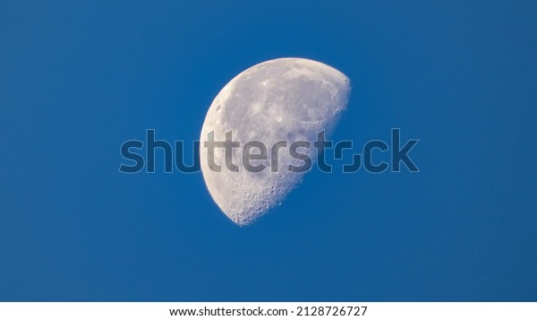 Close up of\
a half full moon with a blue\
background