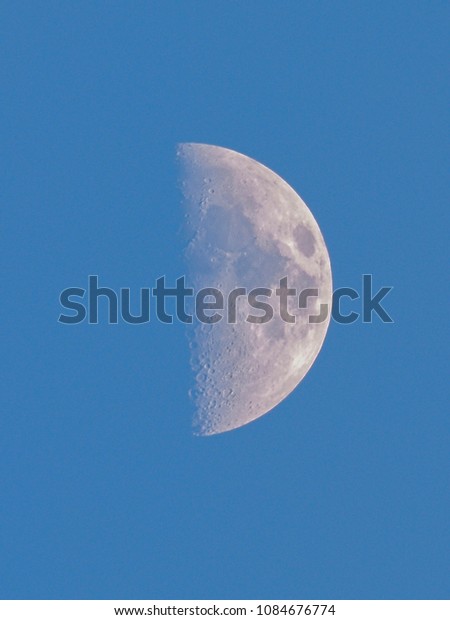 close up\
half moon day time with blue sky\
background