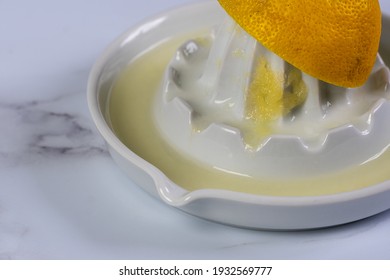 Close Up Of Half A Squeezed Lemon On A Ceramic Juicer, With Juice And Pulp