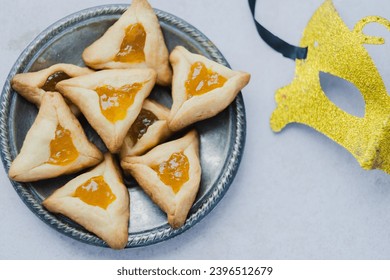 Close up Hamantashen cookies with apricot jam, masks on the table. Purim celebration concept. top view. High quality photo - Shutterstock ID 2396512679