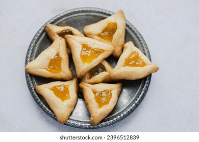 Close up Hamantashen cookies with apricot jam the table. Purim celebration concept. top view. High quality photo - Shutterstock ID 2396512839