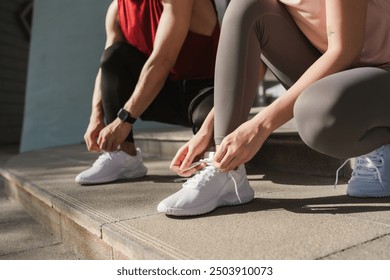 Close up hand of active young man and woman tying shoelace on her running shoes. Preparation before jogging exercise. Fitness and sport activity. Healthy exercise concept. - Powered by Shutterstock