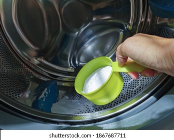 Close Up Hand Adding Baking Soda Powder In To Front-loading Washing Machine For Clean Inside The Washer Drum.