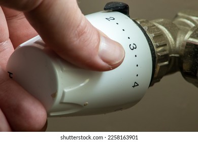 Close up hand adjusting heating temperature. Reducing heating cost in crisis. War in Ukraine. Energy crisis. regulating temperature knob - Shutterstock ID 2258163901