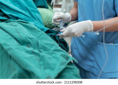 Close up hand Anesthetist in gloves giving medicine injection to iv tube for prepare surgery procedure at operating room. - Powered by Shutterstock