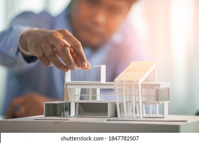 Close up hand of architect making model house modern style,  Asian man architect working in the office.