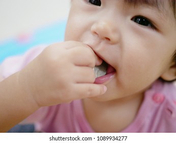 Close Up Of A Hand Of An Asian Baby Girl, 13 Months Old, Holding A Coin Picked From The Floor About To Eat / Put It Into The Baby's Mouth - Baby's Choking Hazard