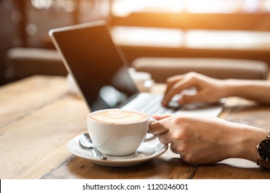 Close Up The Hand Of An Asian Girl Is Freelancer Woman, She Is Working By Using The Laptop Computer And Driking A Cup Of Coffee On Morning In A Coffee Shop Or Her Office.