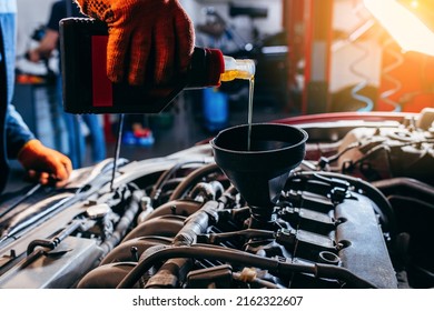 Close up hand of auto mechanic technician replacing and pouring motor oil in modern automobile engine at auto repair service station. - Shutterstock ID 2162322607