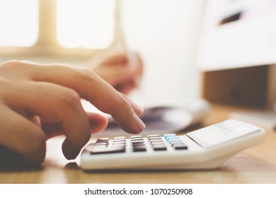Close up hand of businessman doing financial accountant and using calculator with computer desktop - Shutterstock ID 1070250908