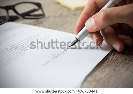 Close up of hand of businessman signing a form. Business man signing contract for future deal. Business man signing legal document. Male hand signing employee contract with a bond. Foto stock © 