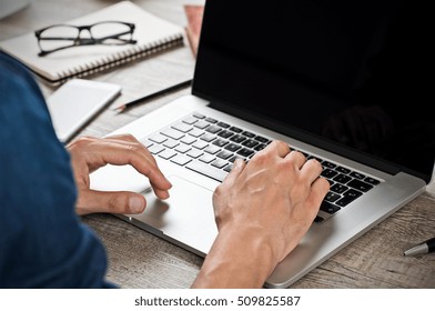 Close Up Of Hand Of Businessman Typing On Laptop Keyboard. Hand Man Writing An Email On A Laptop At Office. Closeup Of Hand Of Casual Business Man Typing On Computer And Sitting At Wooden Desk.