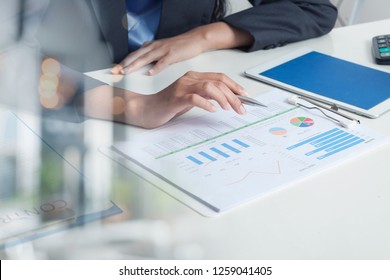 Close UP HAND Of Businesswoman Hold Pen And SPREADSHEET Graph Papers On Table. Audit TAX Return On Investment  Analysis Shareholders And Capital Market.  Auditor And Analytics Concepts