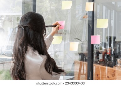 Close up hand businesswoman writing sticky notes on glass wall in office - Powered by Shutterstock