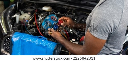 Close up hand. Car air conditioner check and service. Meter measuring equipment for filling air conditioners. Black mechanic man Check car air conditioning system refrigerant recharge