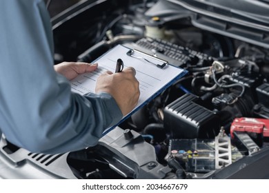 Close up hand car service staff check engine malfunctions and mistake check list in engine room : Car service concept   - Shutterstock ID 2034667679