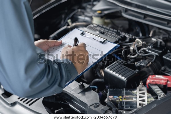 Close\
up hand car service staff check engine malfunctions and mistake\
check list in engine room : Car service concept \
