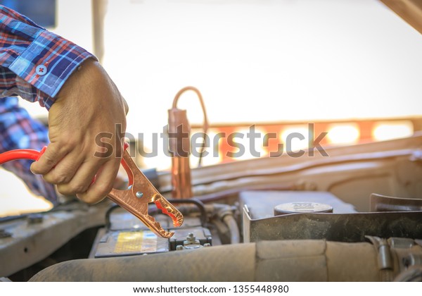 Close up hand of car technician holding cable to\
connect to battery,Car mechanic uses battery jumper cable charge a\
dead battery,A car mechanic uses battery jumper cable transferring\
power,spot focu