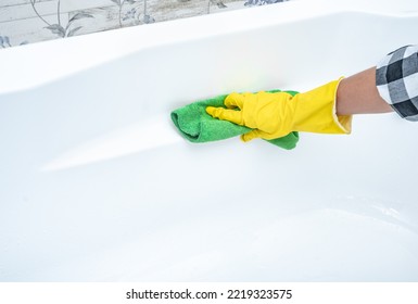 Close up hand cleaning white acrylic bath. Cleaning service. croped hands wearing yellow protect glove using green cloth cleaning white acrylic bath, disinfection and hygiene concept - Powered by Shutterstock