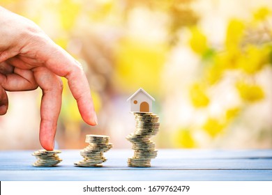 Close Up Of Hand With Climb Up On A Stacking Three Gold Coin With Growing On Steps And Home As Destinations On Sunlight Background, Loan For Real Estate Or Buy A New House In The Future Concept.