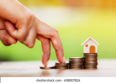 Close up of hand with climb up on a stacking gold coins and home as destinations, Loans for real estate or buy a new house in the future concept.