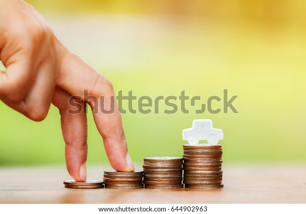 Close up of hand with\
climb up on a stacking gold coins and car as destinations, Saving\
money for buying, or sold a new car for working capital management\
concept.