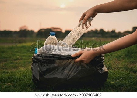 Close up hand collects garbage plastic in a park. A volunteer cleaning plastic bottle on a grass. Environment, recycle and protection concept.