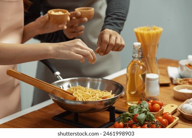 Close up of hand couple chef influencers cooking spaghetti mix ingredient taking to frying pan, putting seasoning and tasty sauce to make good flavor, Concept of presenting homemade food. Postulate.