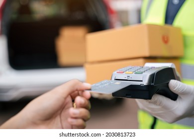 Close Up Of Hand Delivery Man Using Credit Card Swiping Machine To Pay. Hand With Creditcard Swipe Through Terminal For Payment On The Outside Of The Warehouse.