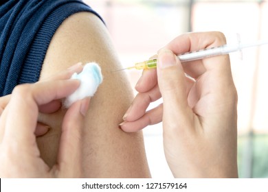 close up hand of Doctor giving patient taking vaccine, flu or influenza shot or taking blood test with needle with shoulder. Nurse with injection or syringe. Medicine, insulin or vaccination. Hospital