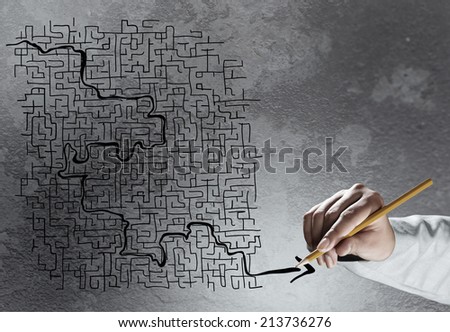 Close up of hand drawing labyrinth on cement wall