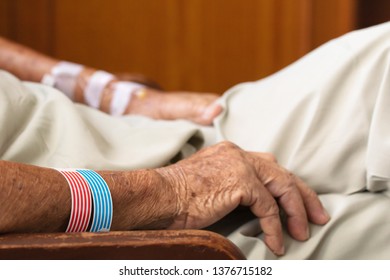 Close Up Hand Of Elderly Over 80 S Asian Man Patient With Intravenous Catheter For Injection Plug, Saline Transfusion Or Brine Drip During The Chemotherapy Of Liver Cancer In Hospital Ward Room

