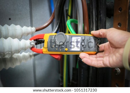Close up hand of engineer to use digital clip ampere meter clamp to power cable for check Power current
