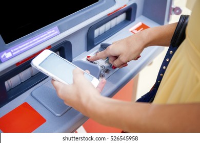 Close Up Of Hand Entering Pin At An ATM. Finger About To Press A Pin Code On A Pad. Security Code On An Automated Teller Machine. Female Arms, ATM - Entering Pin