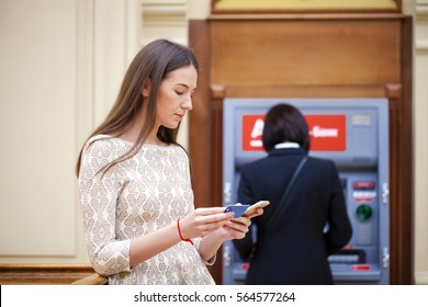 Close Up Of Hand Entering Pin At An ATM. Finger About To Press A Pin Code On A Pad. Security Code On An Automated Teller Machine. Female Arms, ATM - Entering Pin