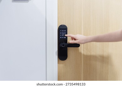 Close up of a hand entering a pin code on a modern digital door lock for smart home security system.