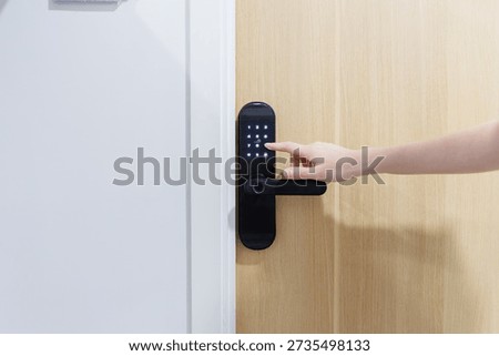 Close up of a hand entering a pin code on a modern digital door lock for smart home security system.