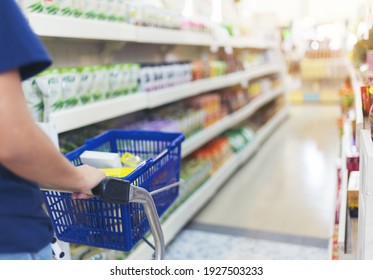 Close Up Hand Of Female Shopper With Trolley, Shopping Cart At Supermarket. Defocused Bokeh Light Background
