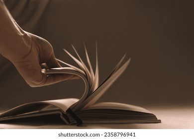 Close up of a hand flipping through book in a contrast warm light - Powered by Shutterstock