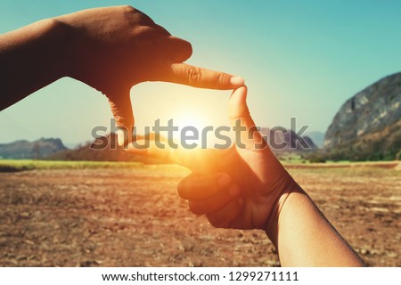 close up hand framing view distant over sunrise