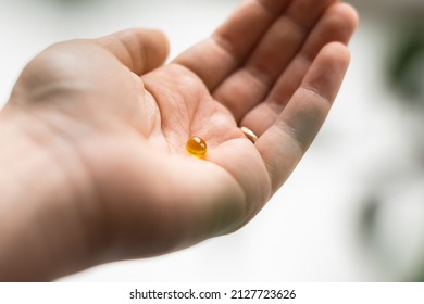 Close Up Of Hand Full Of Yellow Softballs. Taking Supplements, Vitamin D Or Omega. Wellbeing Biohacking Concept