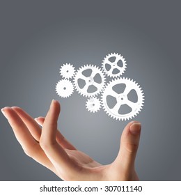 Close up of hand and gears mechanism on gray background