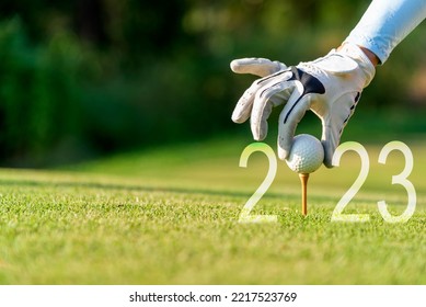 Close up hand Golfer woman putting golf ball for Happy New Year 2023 on the green golf for new healthy.  copy space. Healthy and Holiday Concept