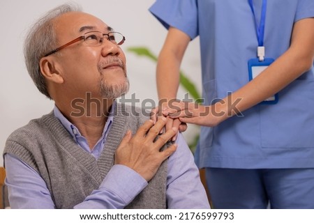 Close up hand of hands of nursing aide holding and patting winkled hand of a patient.Domiciliary care for sick elderly.