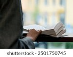 close up hand hold book in bookstore near the window a beautiful student is sitting reading books preparing for exams in front of the window